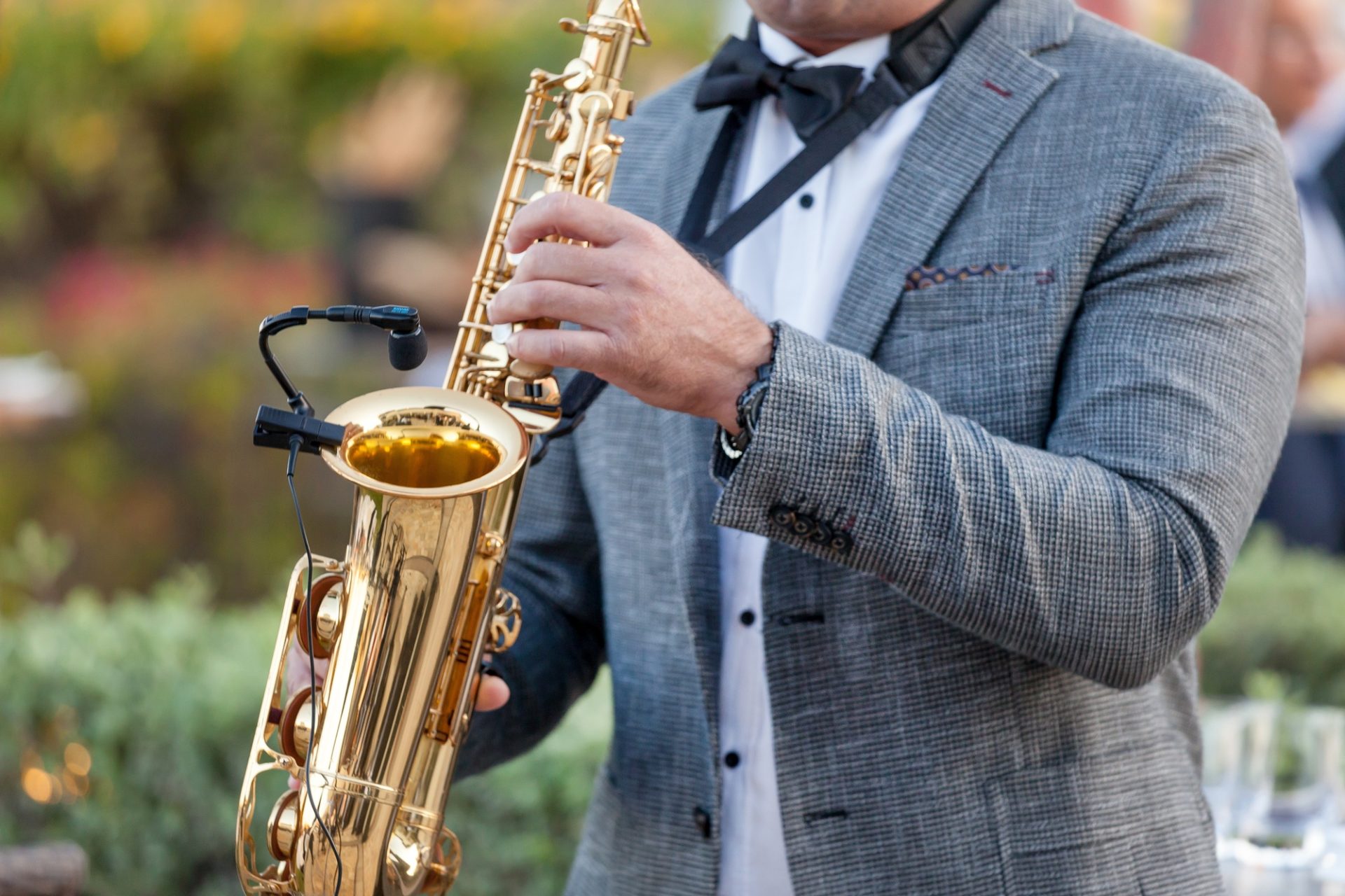 Homme en costume jouant du saxophone doré en plein air