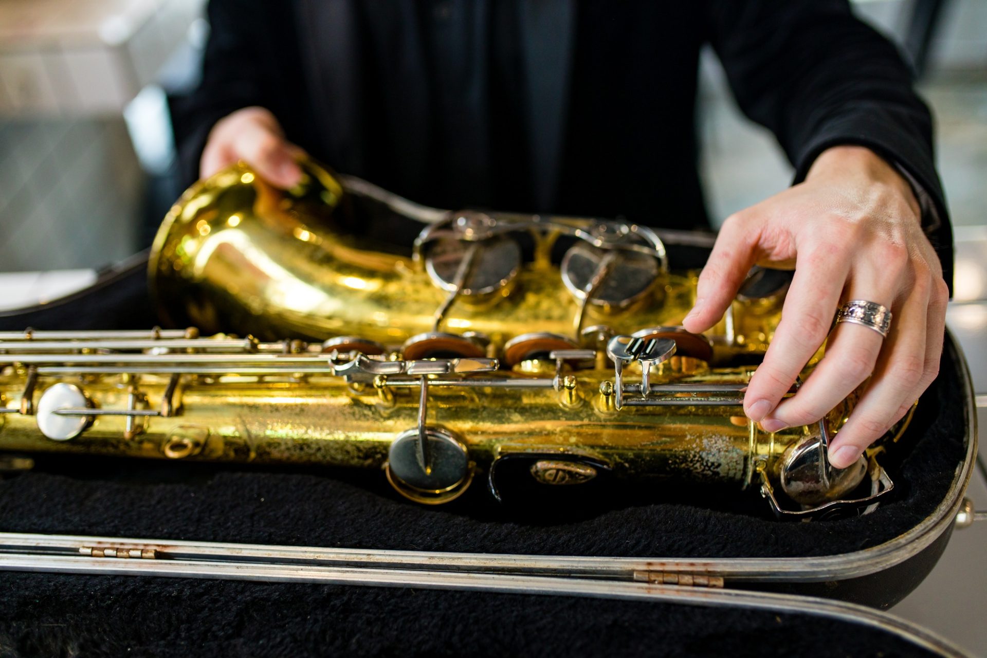Saxophone doré posé dans un étui, main le rangeant soigneusement